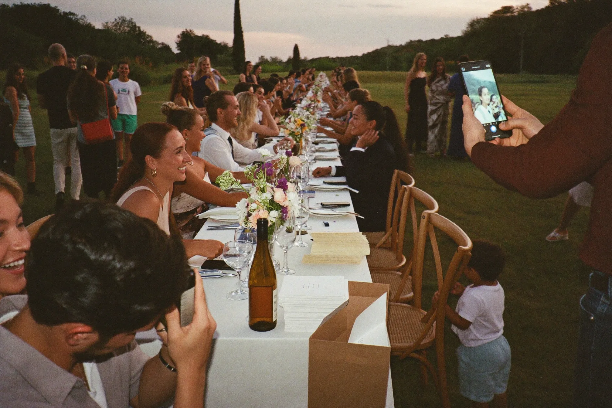 Invitati di età diverse usano un cartoncino per la caccia fotografica al tavolo del matrimonio.