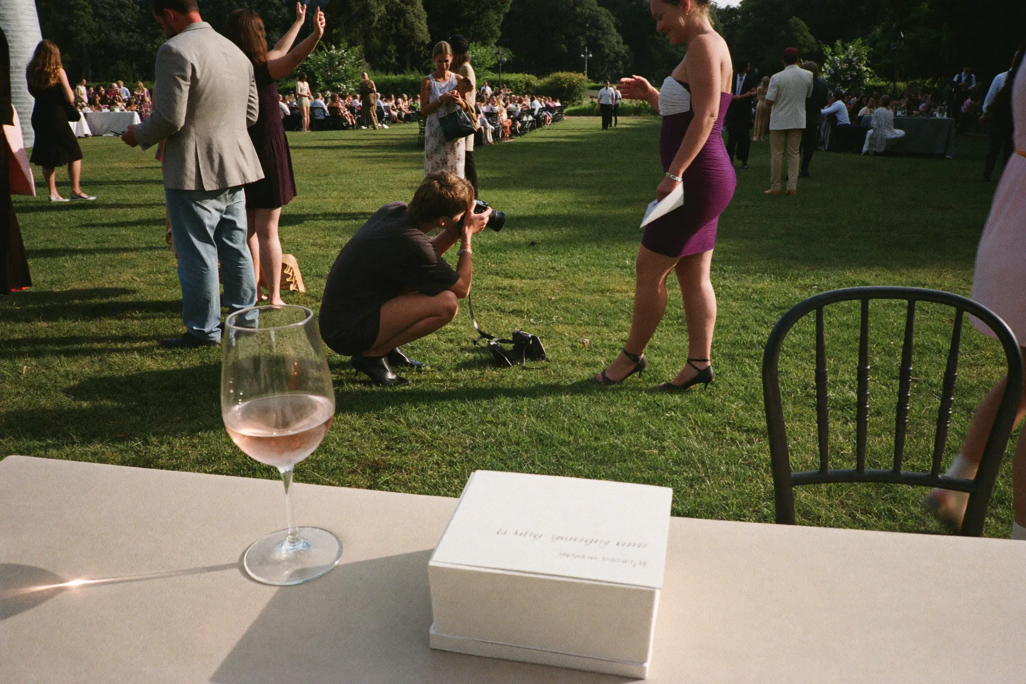 Des invités de plusieurs générations utilisent une carte de défi photo à leur table de mariage.