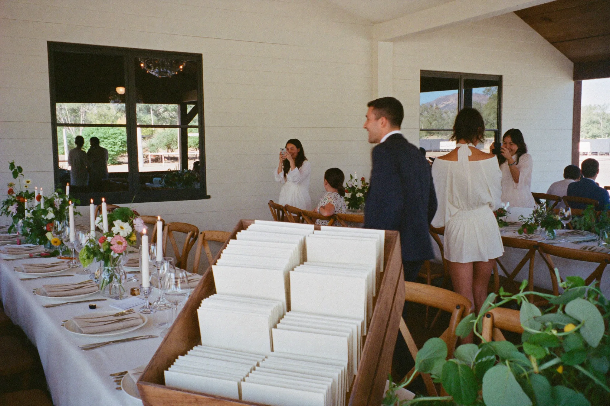 Bruiloftsgasten van verschillende leeftijden gebruiken een kaart voor een foto-speurtocht aan tafel.