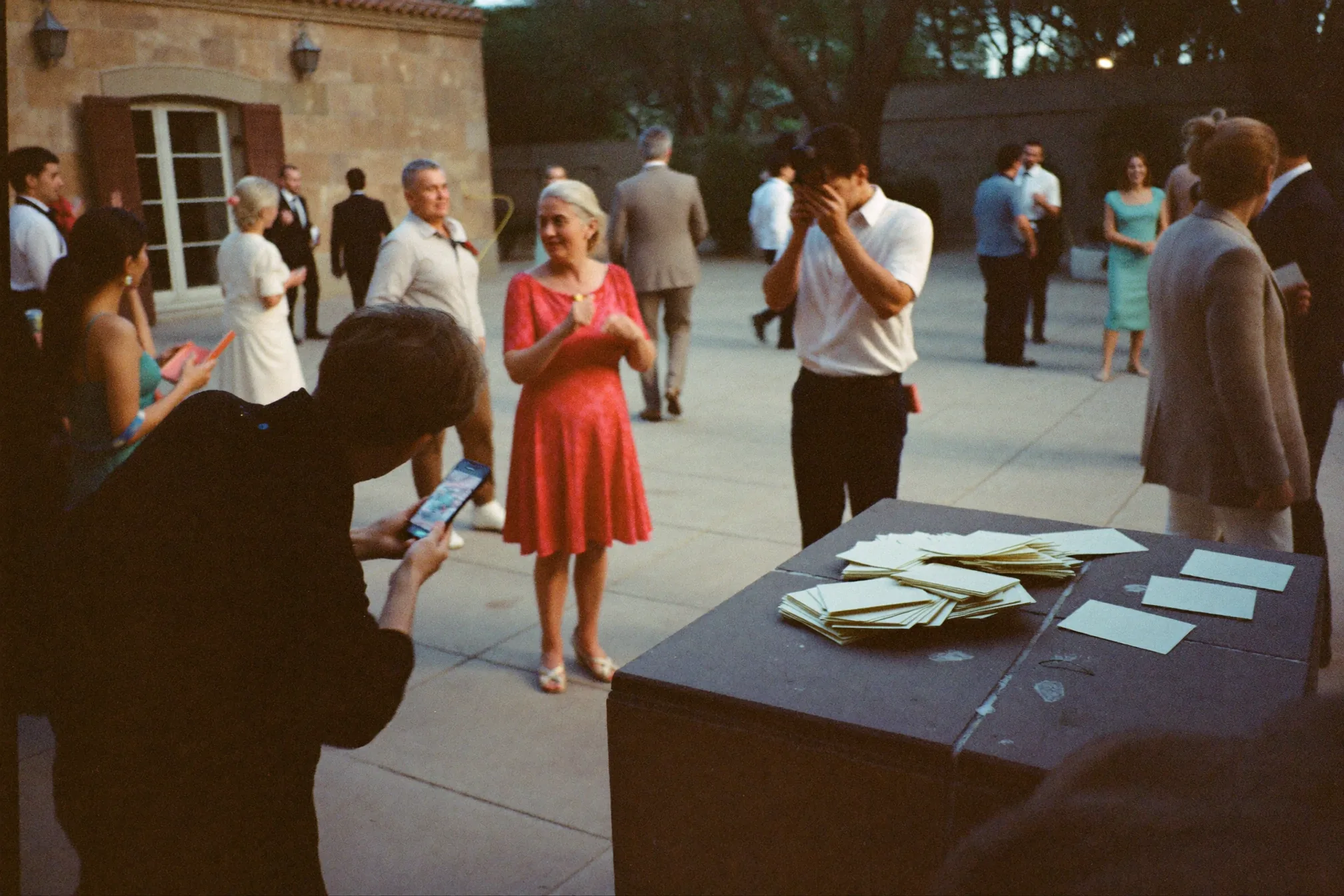 Invitados de varias generaciones usan una tarjeta de gincana fotográfica en la mesa de una boda.