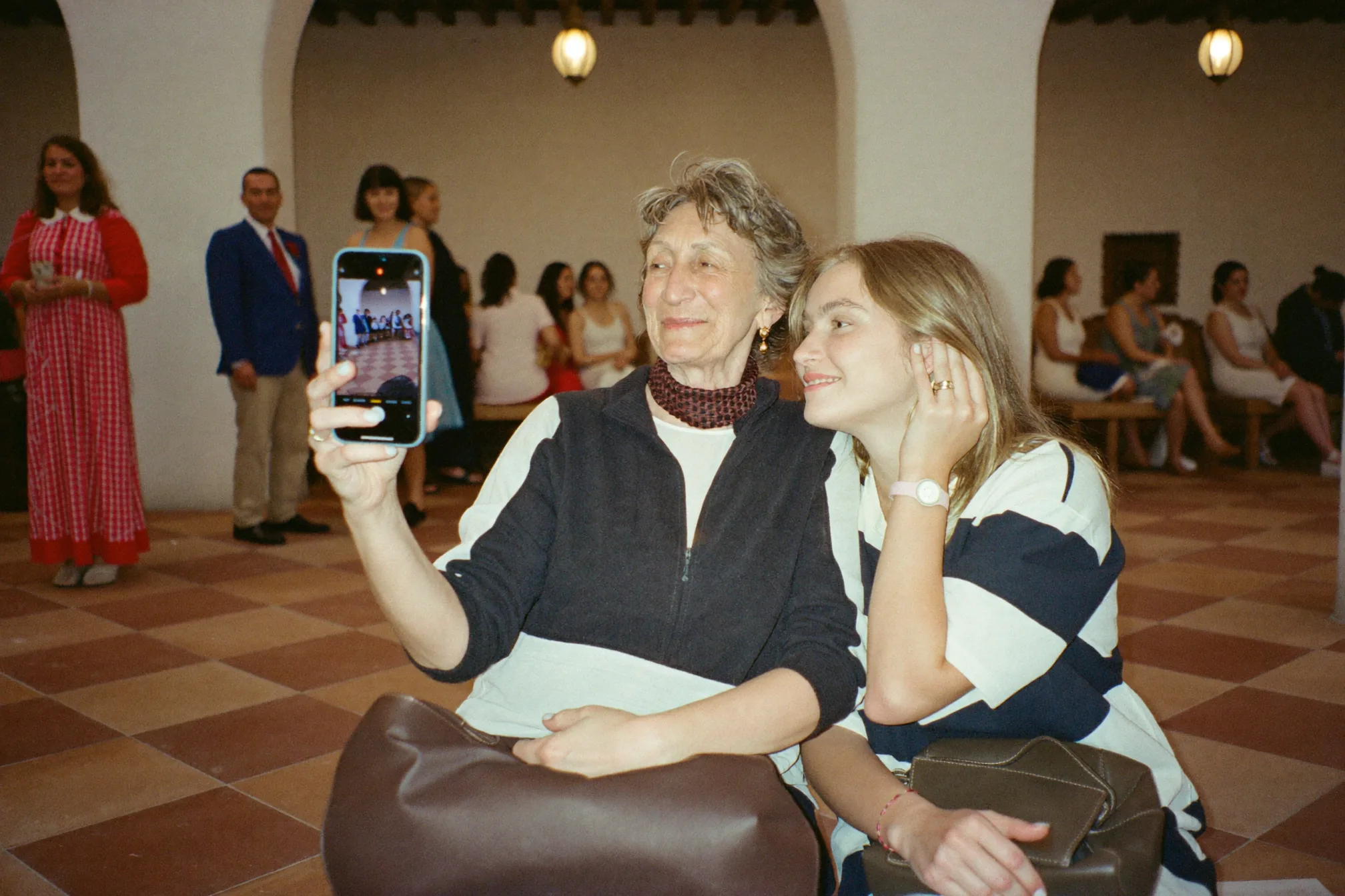 Una invitada graba un mensaje de vídeo junto a un cartel con código QR en una mesa de boda con iluminación suave