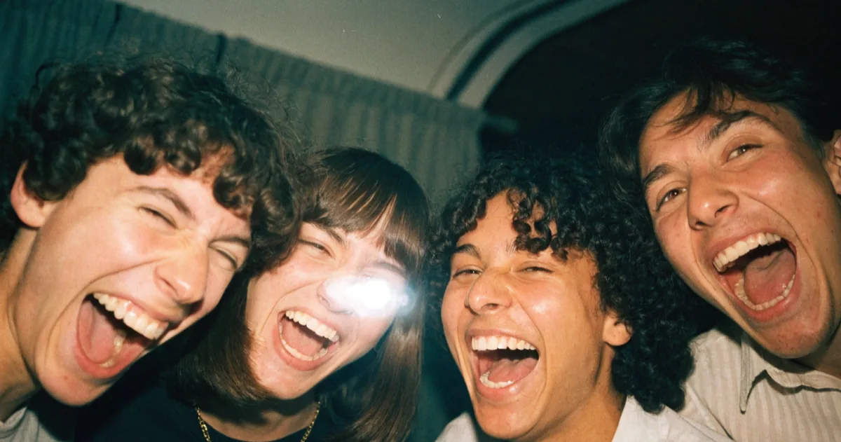 Four friends lean into a photo booth frame side by side as the countdown light flashes.
