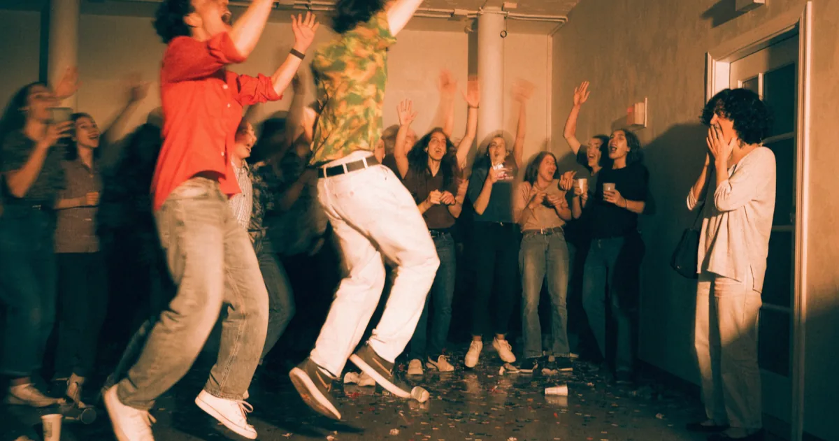 Friends leaping up and shouting as the lights come on and the guest of honour stops in the doorway of a surprise birthday party