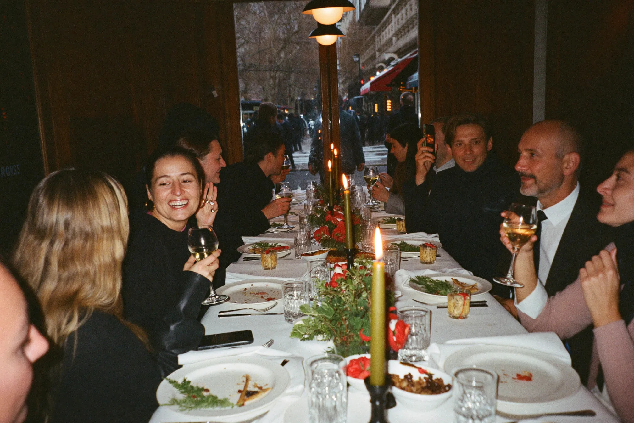 Fête de Noël au bureau dans une salle de réunion ordinaire éclairée de guirlandes et de bougies, des collègues discutant autour d'une longue table