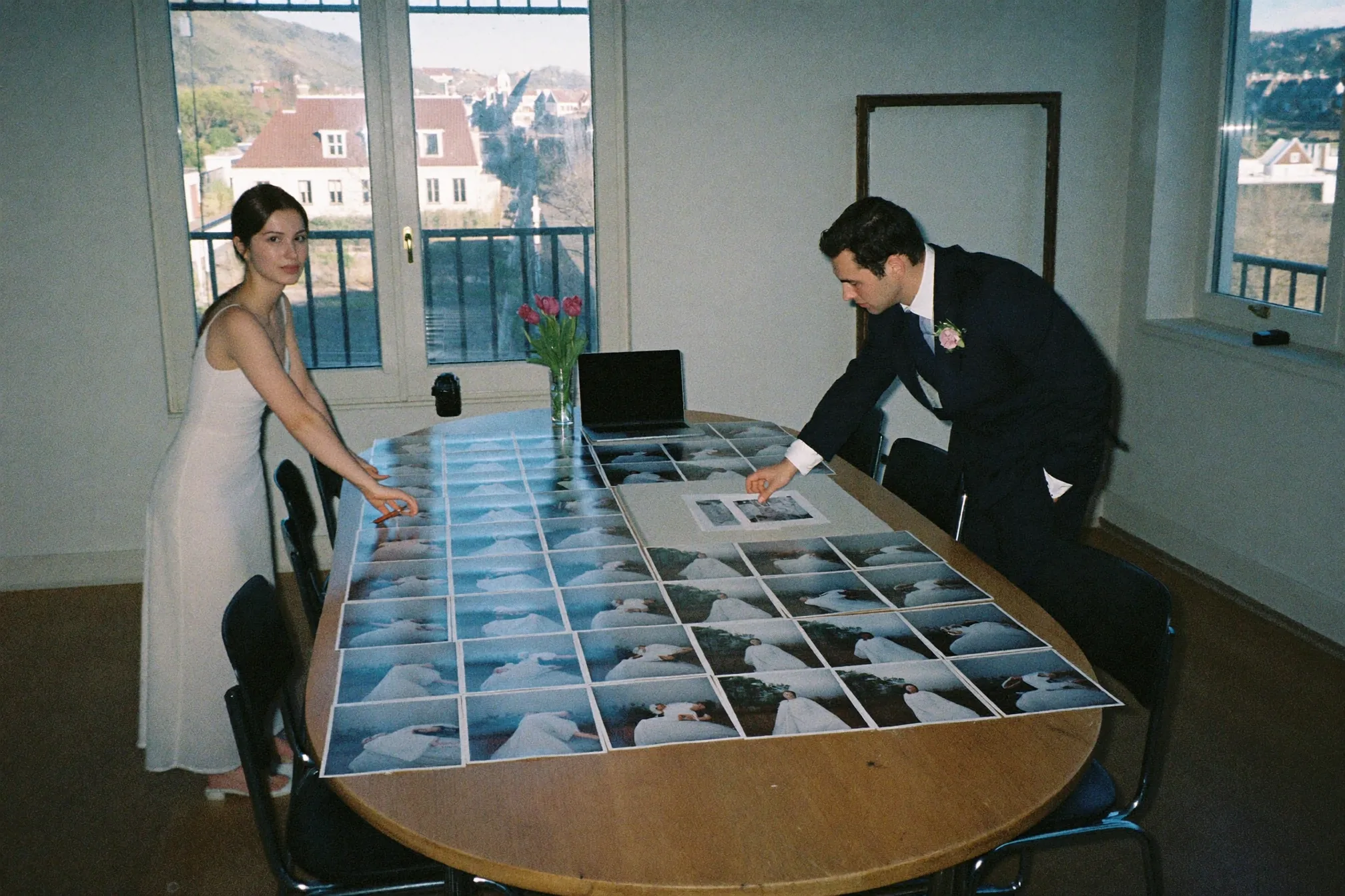 Stel aan de keukentafel dat trouwfoto's bekijkt op een laptop, met een externe schijf en een paar afdrukken ernaast
